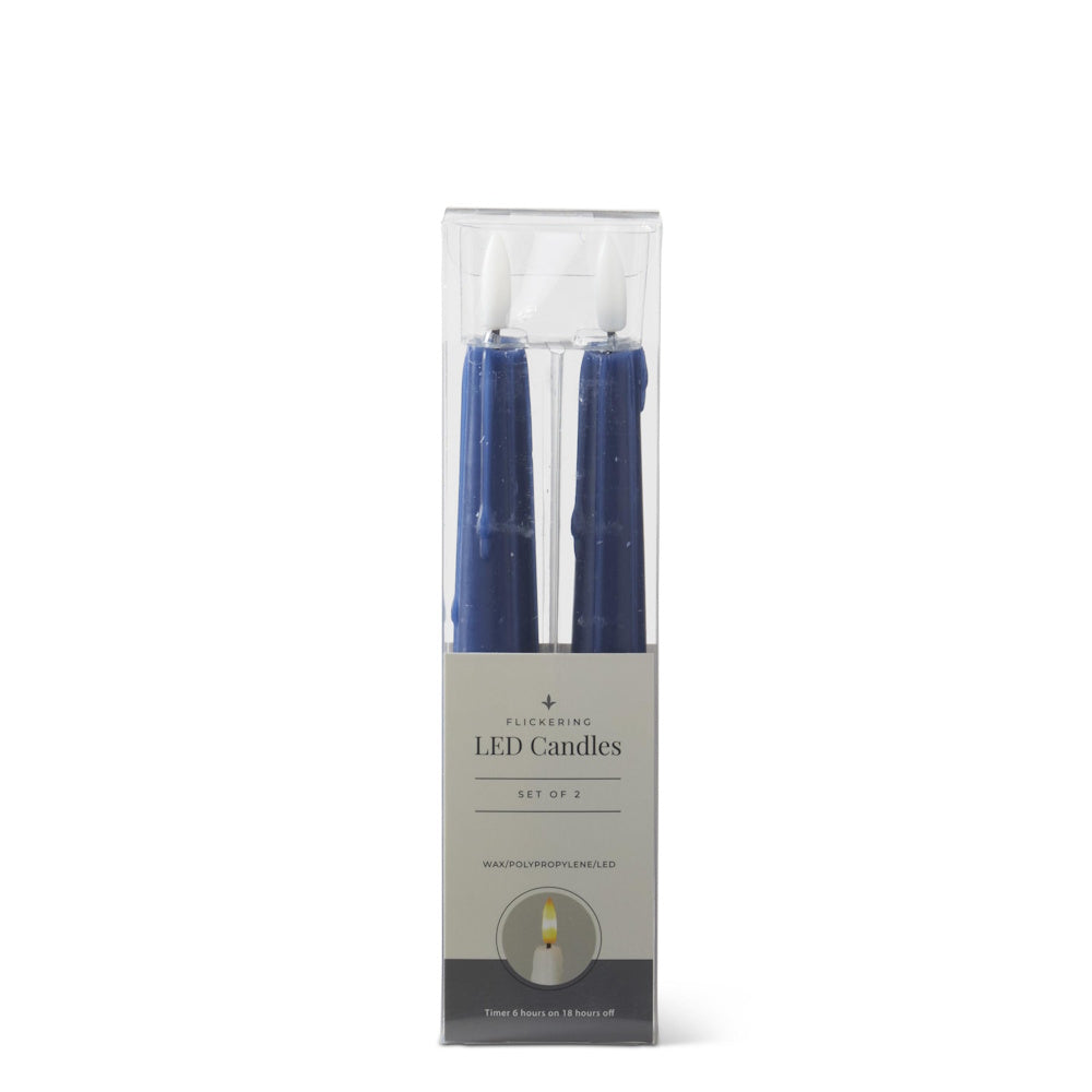A set of two dark blue LED drip taper candles inside their clear plastic and grey product packaging.