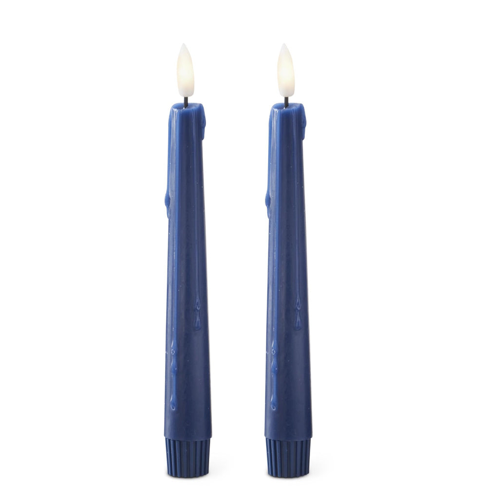 Two dark blue taper candles with molded wax drips and glowing faux LED flames on a white background.