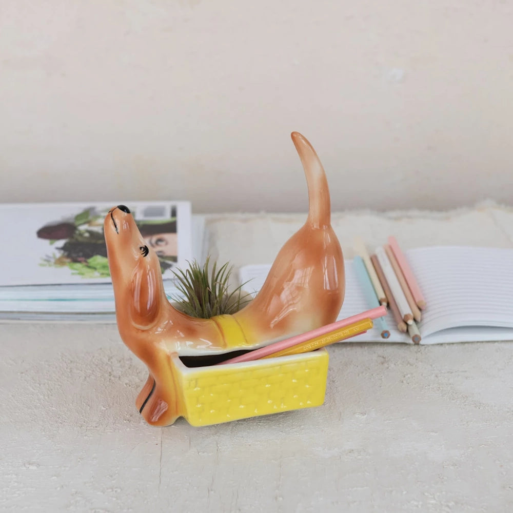 Ceramic dachshund dog planter and pencil holder in tan and yellow, featuring a small air plant and colored pencils.