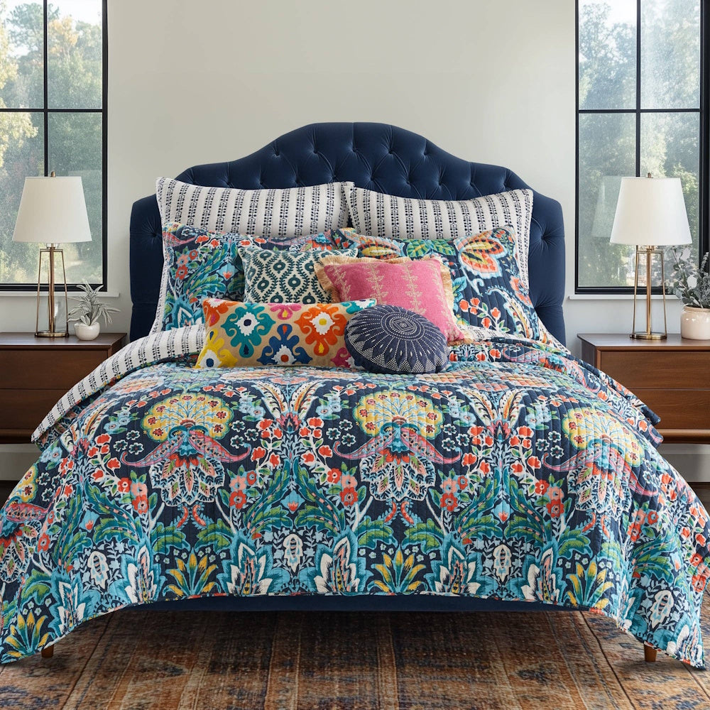 Bed set featuring a colorful bohemian floral quilt in blue, teal, orange, and pink with accent pillows.