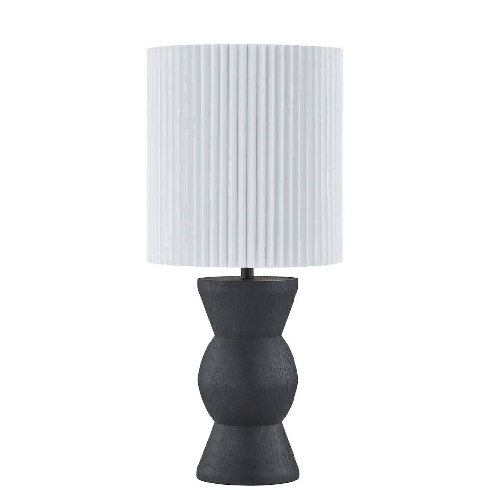 Black hourglass table lamp with textured wood grain base and white pleated drum shade.