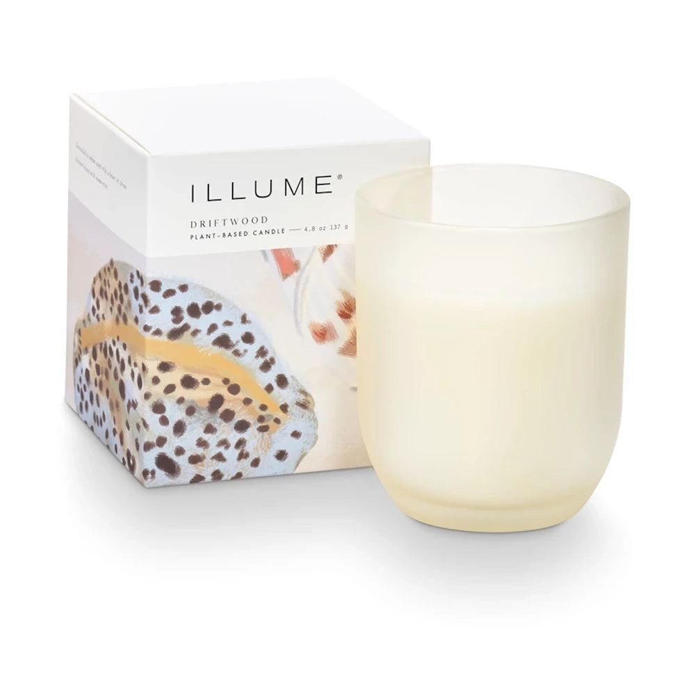 Illume Driftwood plant-based candle in a frosted glass jar next to its decorative white and patterned box.