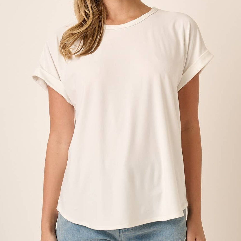 Woman wearing a white round neck dolman short sleeve knit top with cuffed sleeves and light wash jeans.