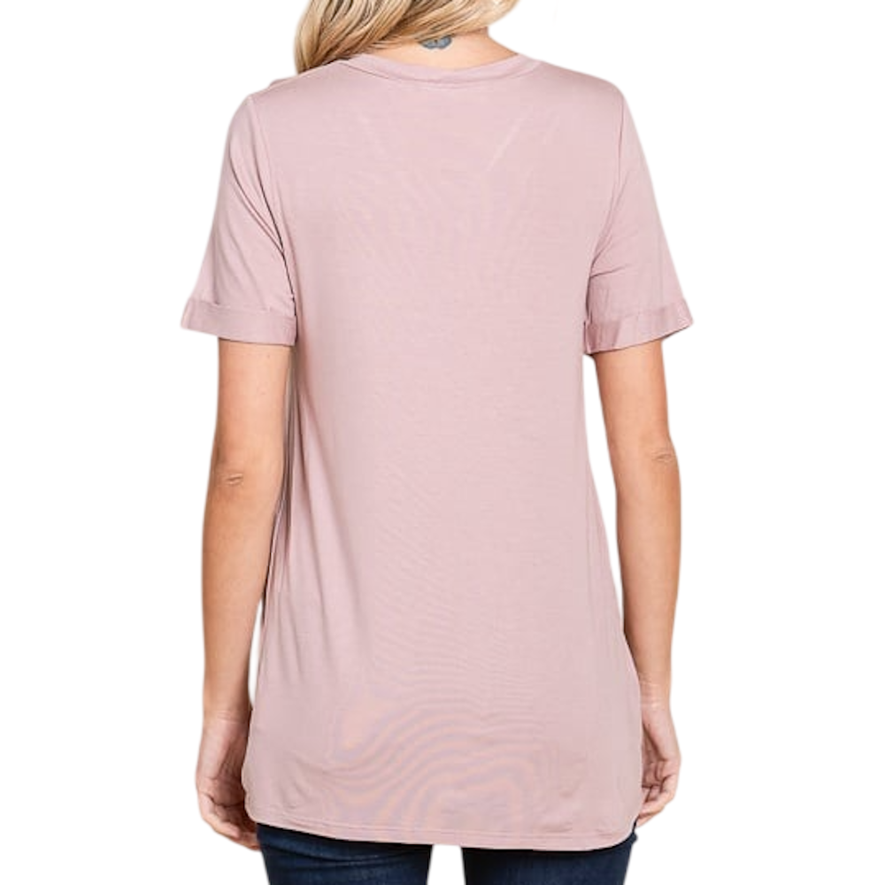Back view of a woman wearing a light pink, short-sleeved tunic t-shirt.