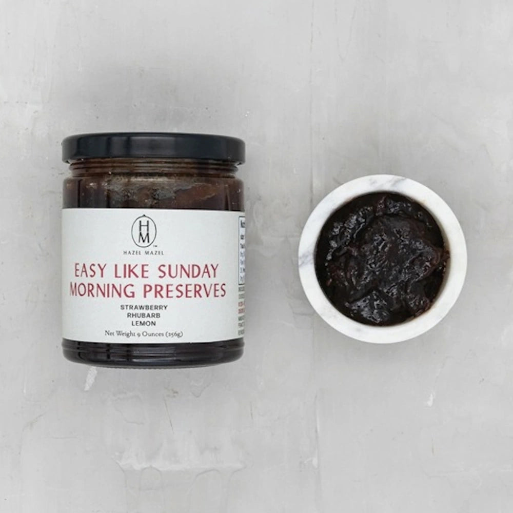 Glass jar of Easy Like Sunday Morning Preserves next to a small marble dish filled with dark jam.