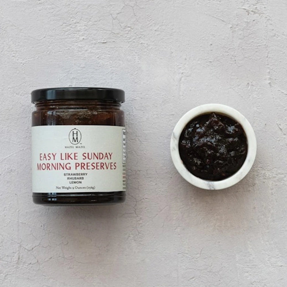 Jar of Hazel Mazel Easy Like Sunday Morning Preserves next to a small marble bowl of dark jam.
