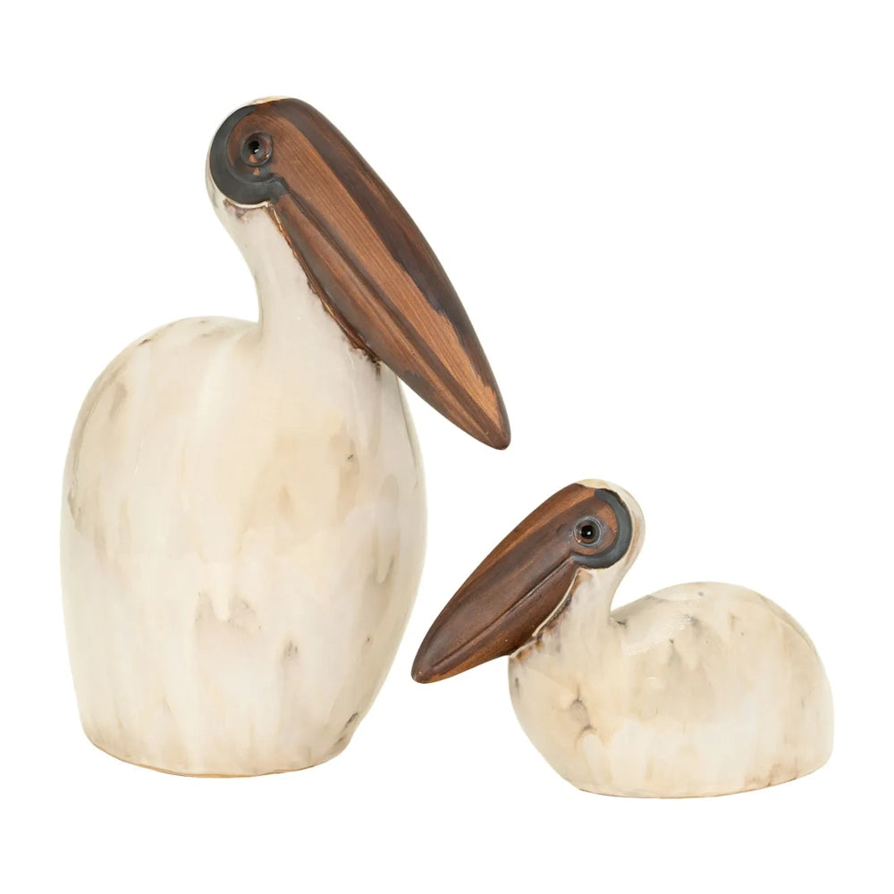 Two ceramic pelican sculptures in off-white with brown beaks, one large standing and one small resting.