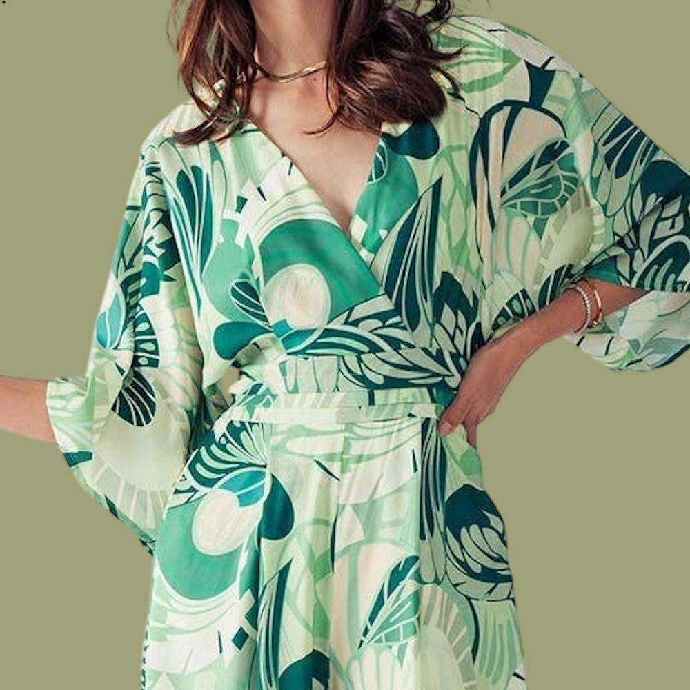 Close-up of a person wearing a green and cream floral jumpsuit with a deep V-neck and wide sleeves.