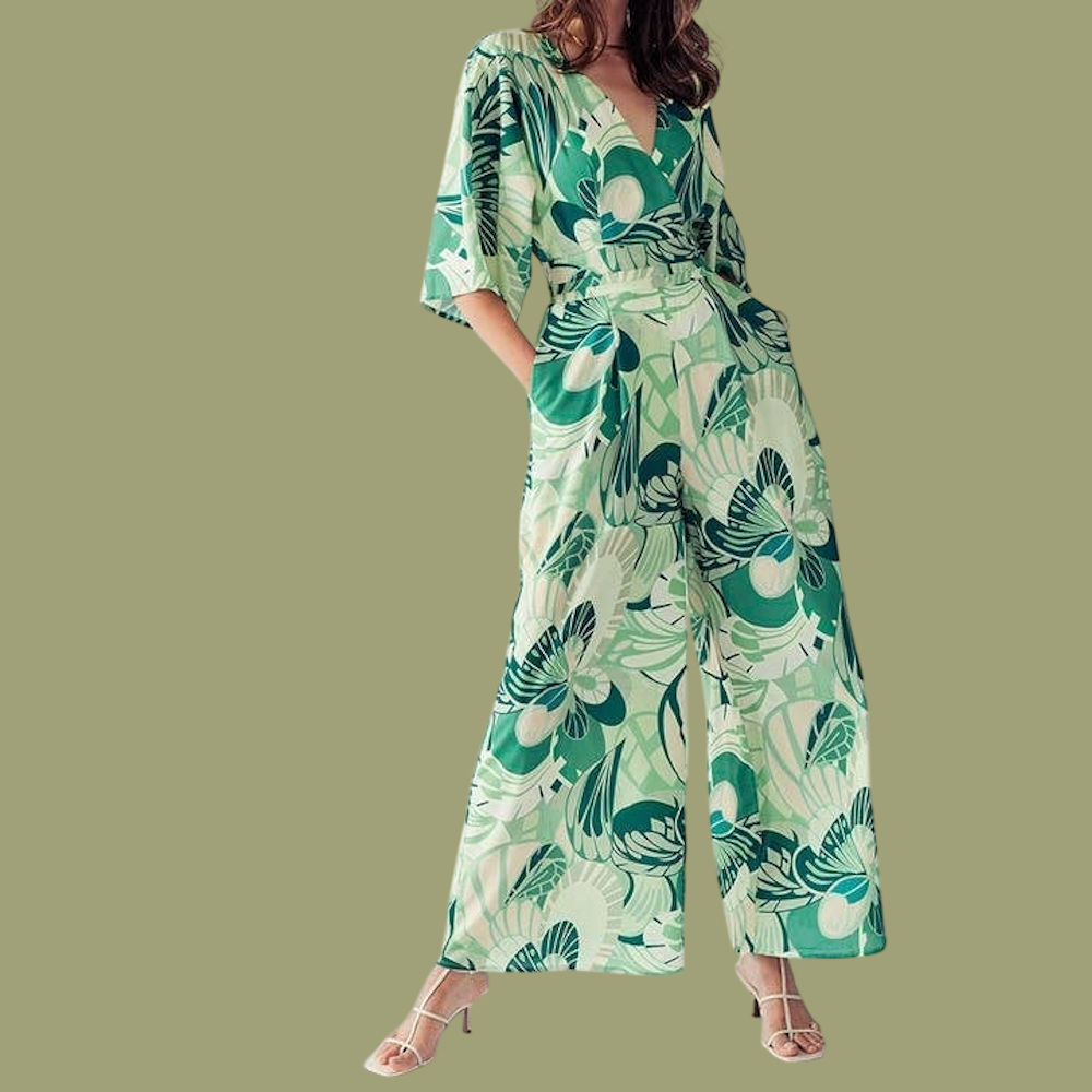 Woman wearing a green patterned, wide-leg jumpsuit with a V-neck and short sleeves.