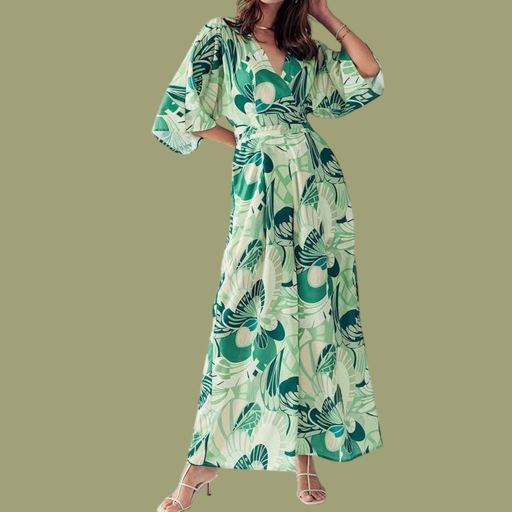 Woman wearing a green and cream floral V-neck jumpsuit with wide legs and flutter sleeves.