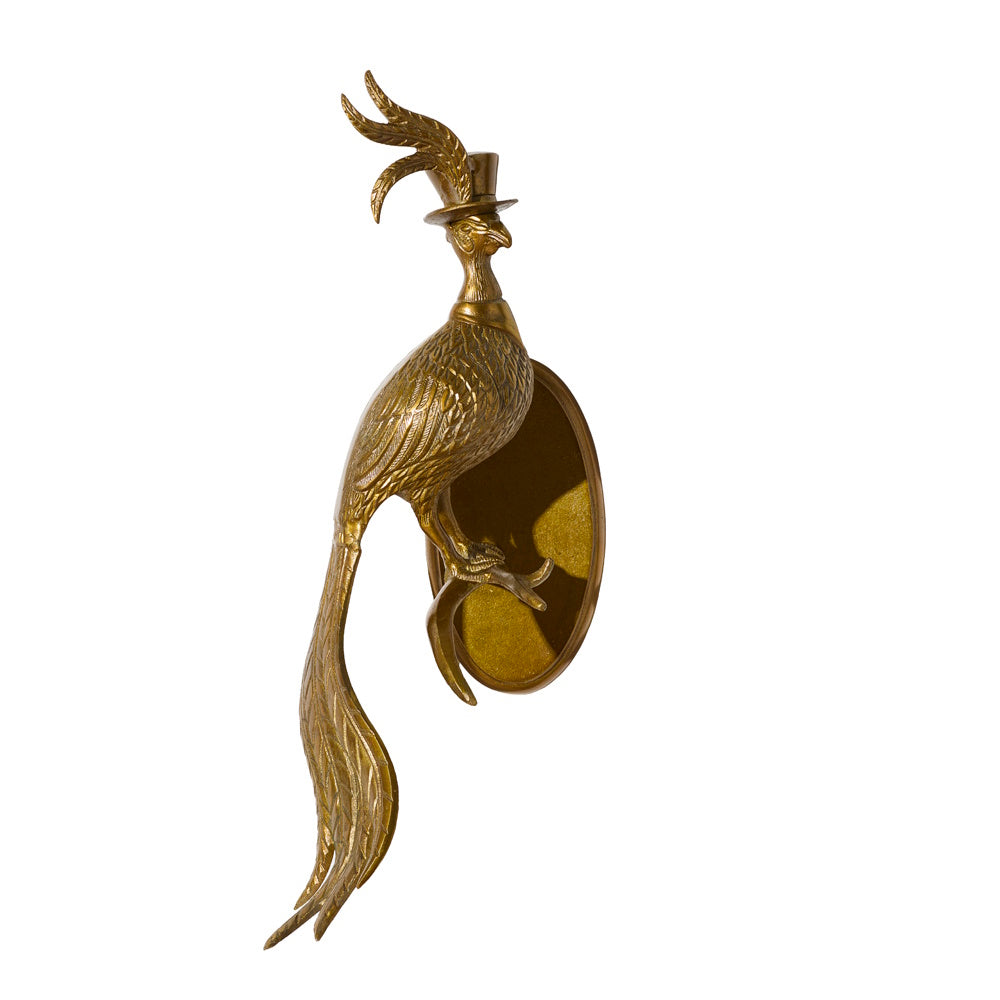 Brass wall-mounted sculpture of a long-tailed bird wearing a top hat, perched on an oval backing.