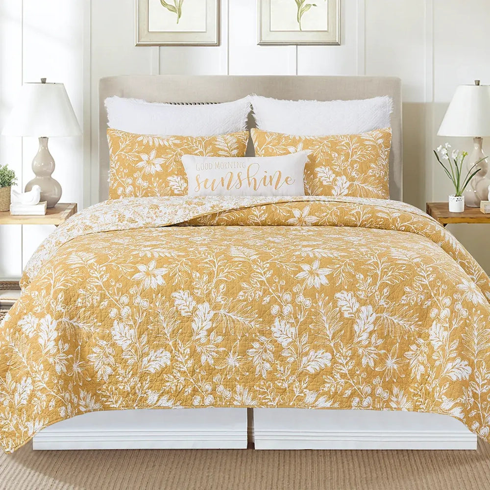 Yellow and white floral quilt set on a bed with matching pillows and a "Good Morning Sunshine" accent pillow.