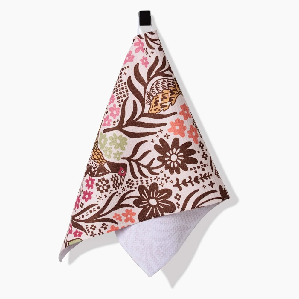 A cream-colored bar towel hanging from a loop, featuring an autumn pattern of game birds and brown flowers.