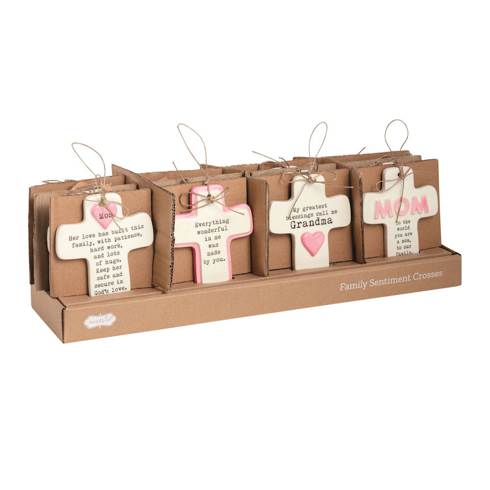 Display of ceramic family sentiment crosses for Mom and Grandma in cardboard packaging with twine hangers.
