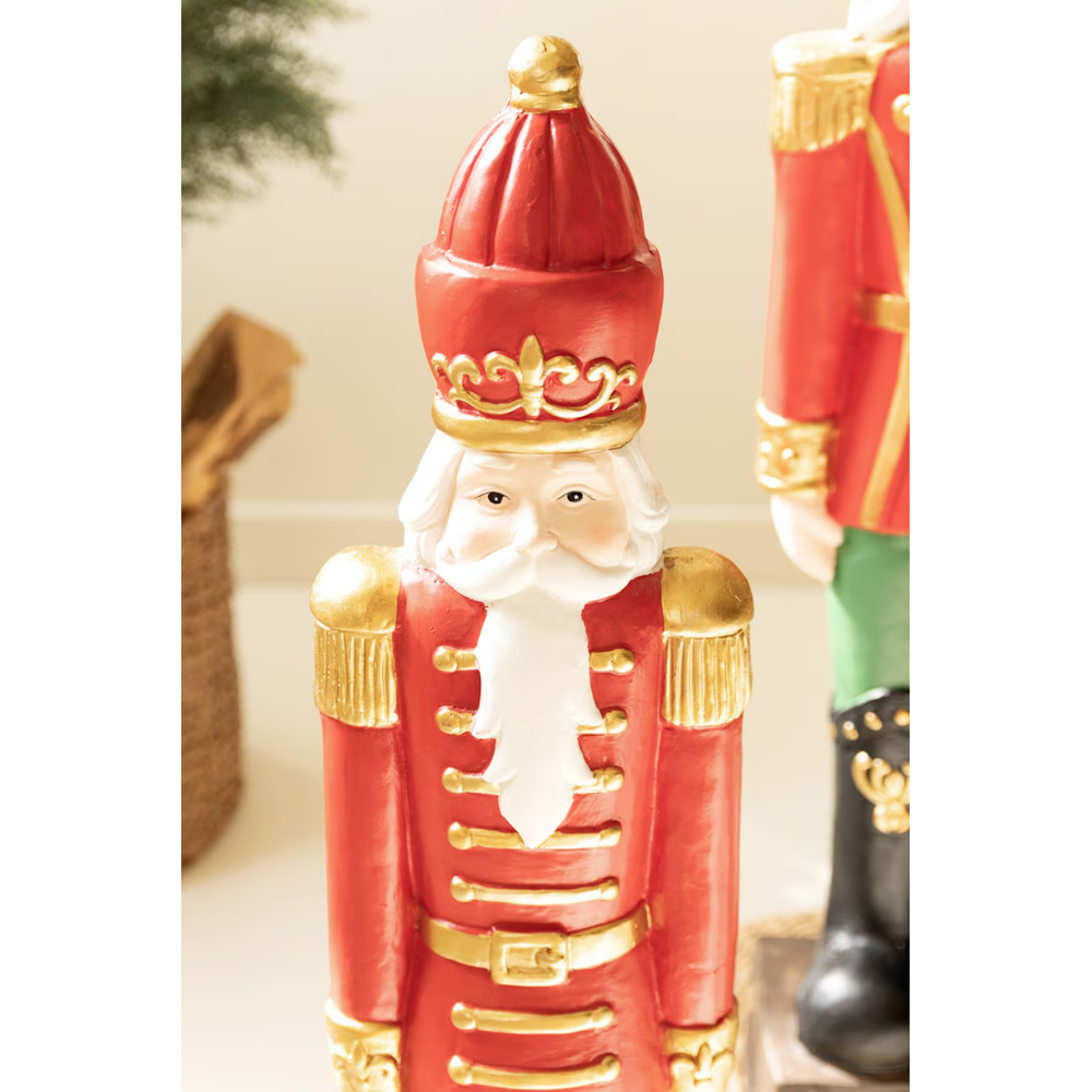 Close-up of a faux concrete Christmas nutcracker soldier statue with gold accents and a white beard.