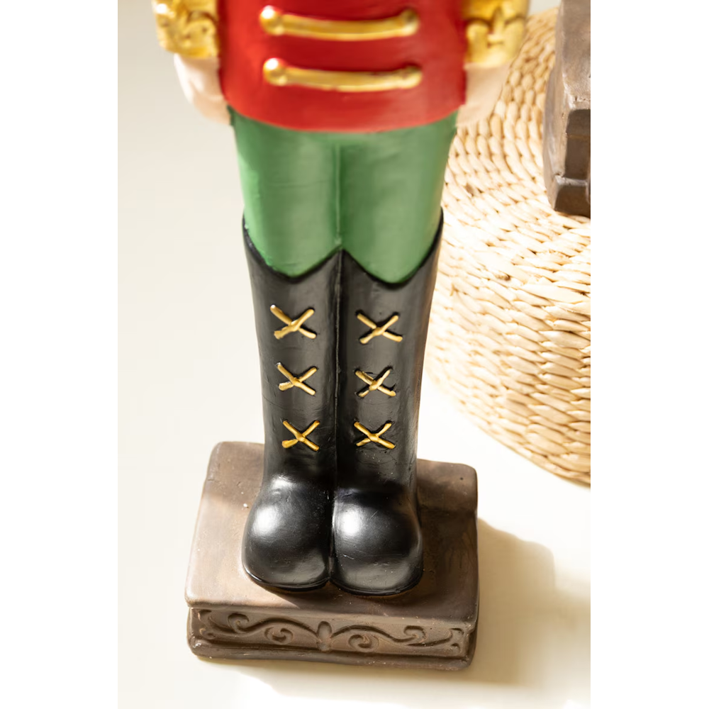 Close-up of gold-laced black boots on a faux concrete nutcracker soldier statue.
