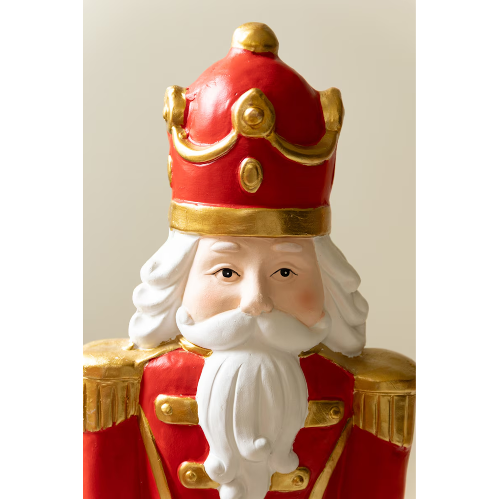 Close-up of a faux concrete nutcracker king statue wearing a red crown with gold trim.
