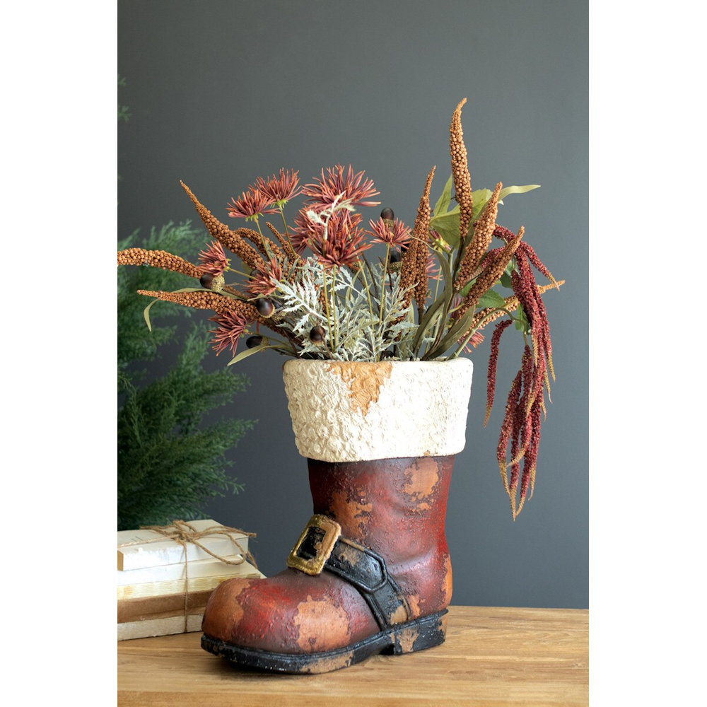 Rustic faux-concrete Santa boot planter filled with autumn floral stems on a wooden table.