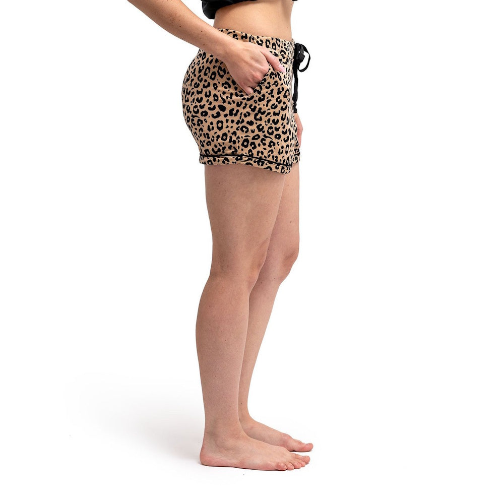 Side view of a person wearing leopard-print pajama shorts with a drawstring waist and pockets.