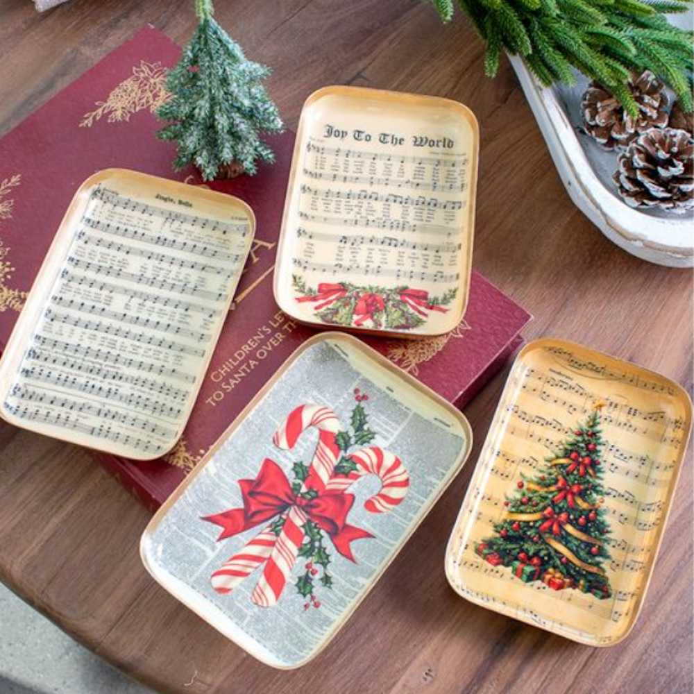 Four small vintage holiday trays with sheet music, candy canes, and Christmas tree designs.