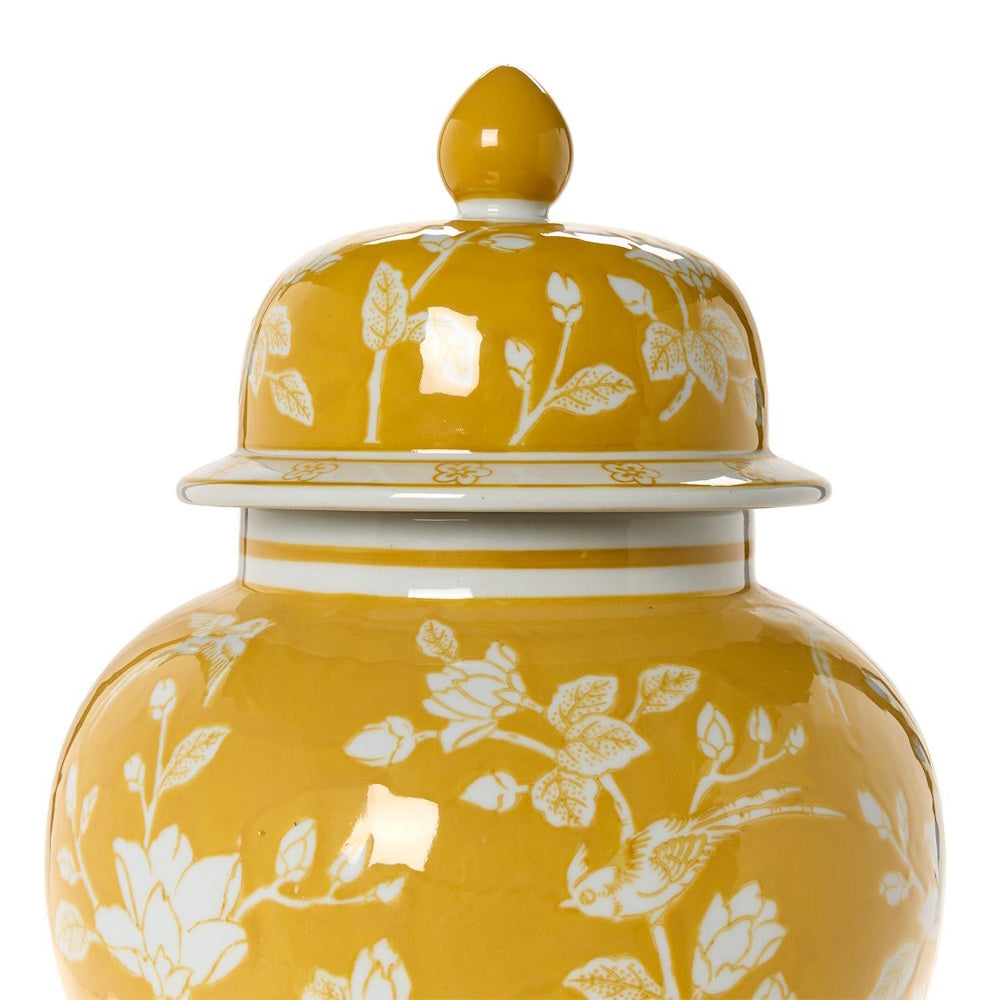 Close-up of a yellow and white ceramic temple jar with a floral and bird pattern and matching lid.
