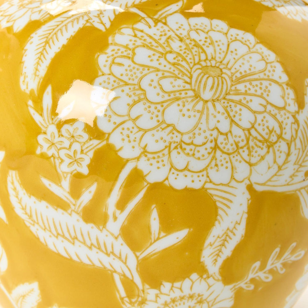 Close-up of a glossy yellow ceramic surface featuring detailed white floral patterns.