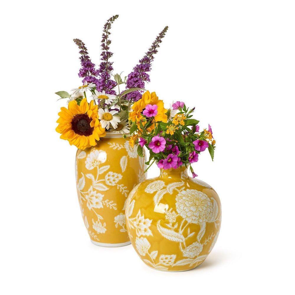 Two bright yellow floral-patterned vases filled with colorful fresh flowers on a white background.