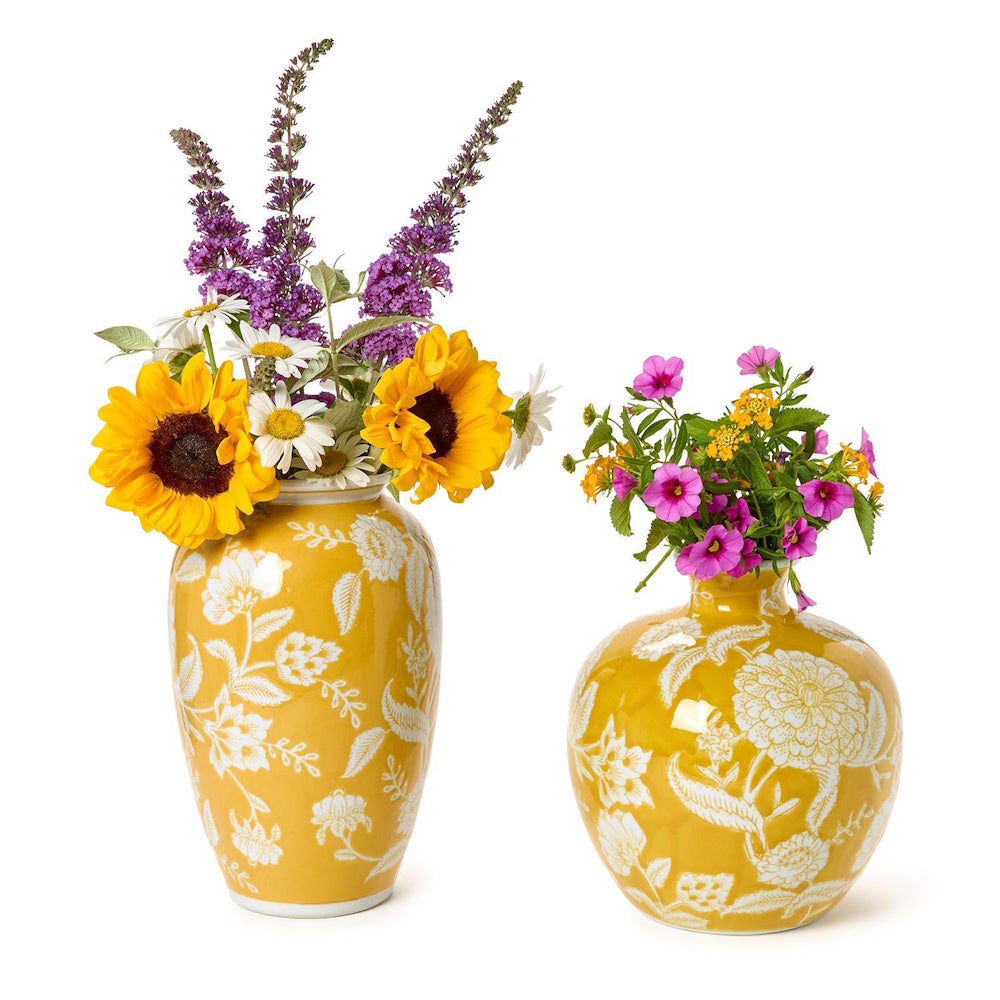 Two bright yellow floral ceramic vases filled with colorful fresh flowers on a white background.