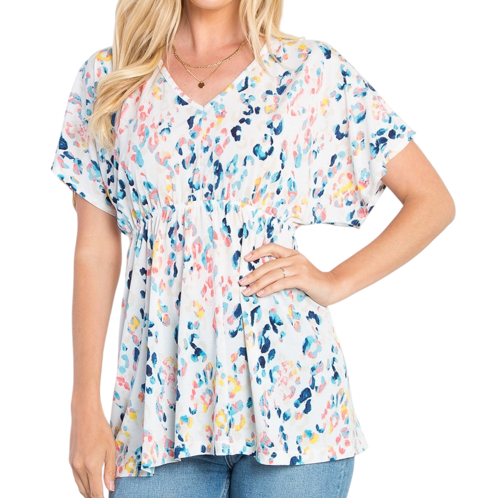 A woman wearing a colorful, abstract animal-print babydoll top with short flutter sleeves and a V-neck.
