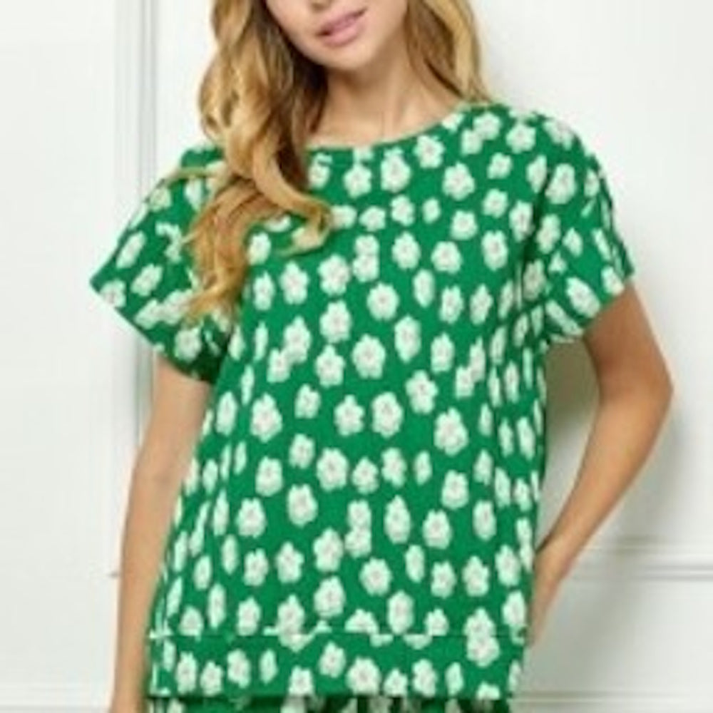 Woman wearing a green short-sleeve top with an all-over white floral pattern.