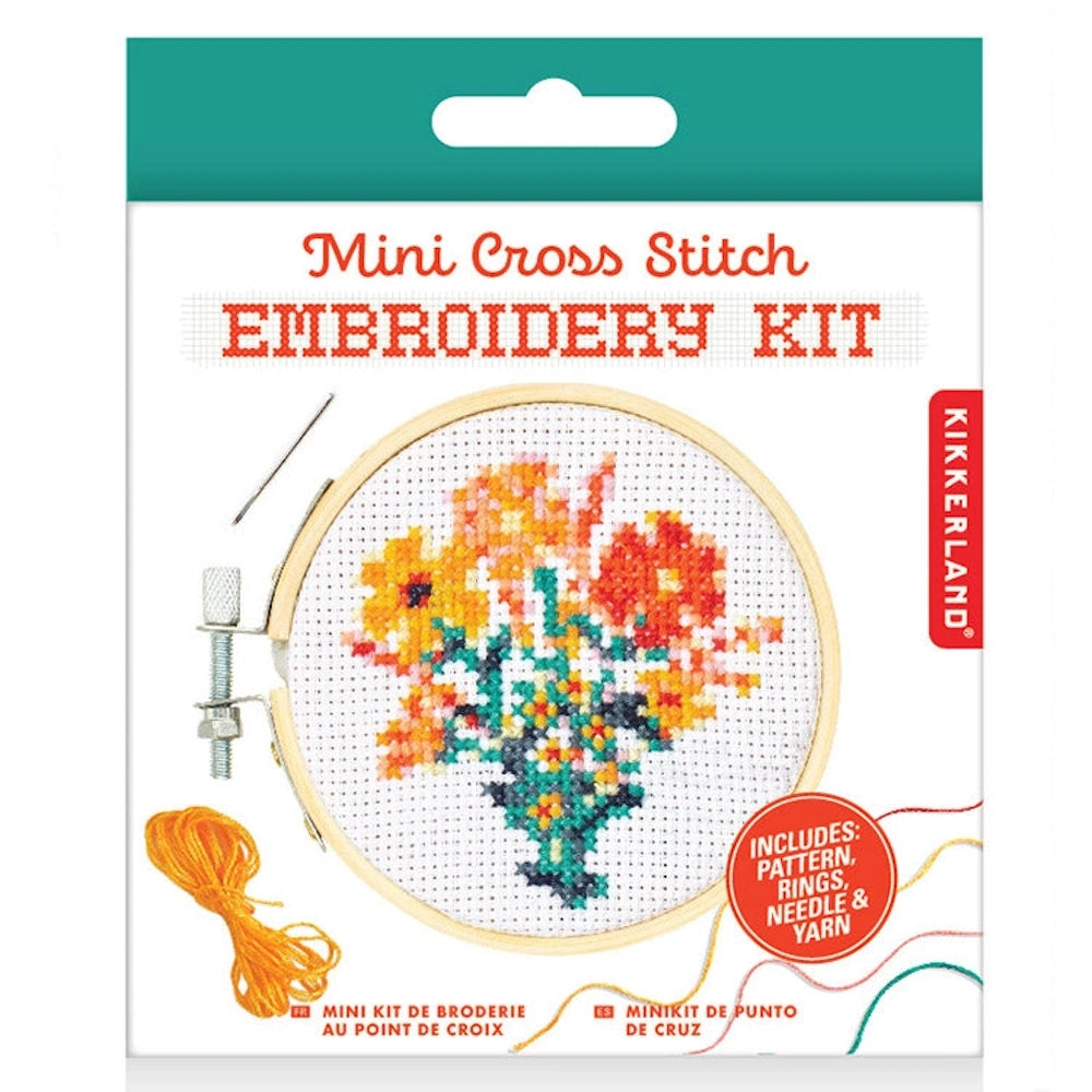 Kikkerland Mini Cross Stitch Embroidery Kit featuring a colorful floral bouquet pattern with needle and orange yarn.