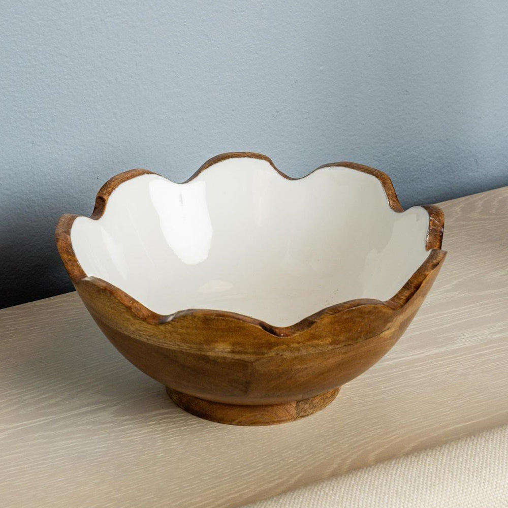 Fluted mango wood bowl with white enamel interior and scalloped edges on a wooden surface.