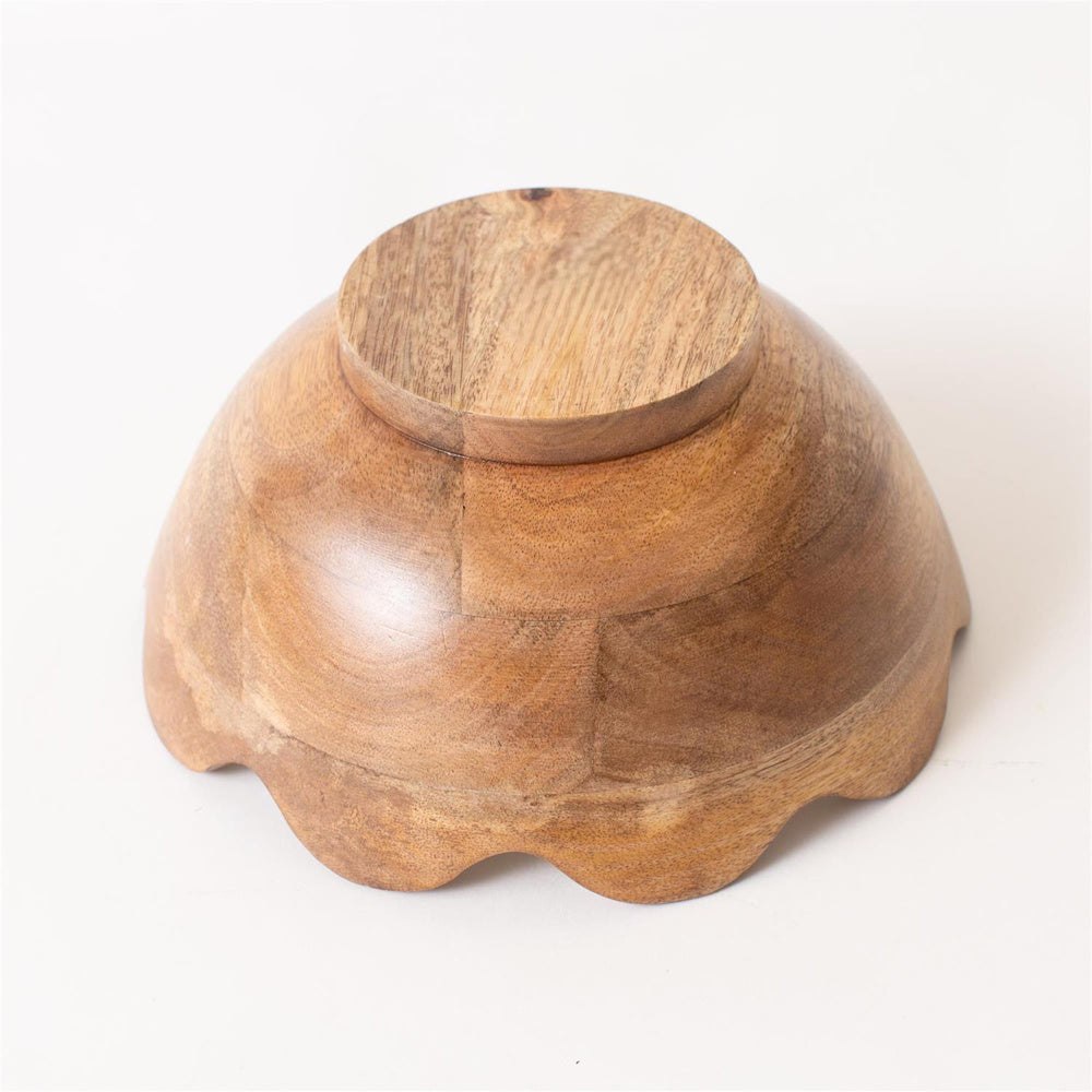 Bottom view of a fluted mango wood bowl showing natural grain textures and a scalloped rim on a white background.
