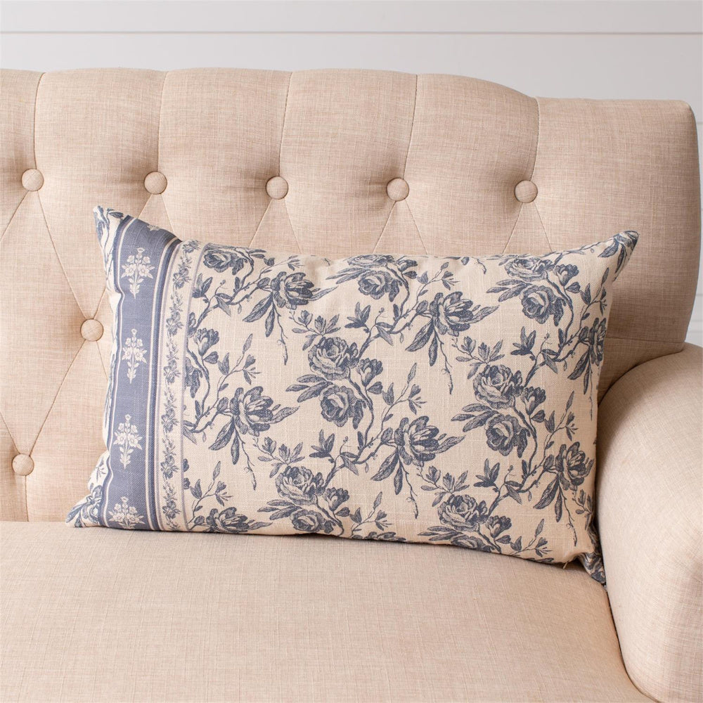 French blue floral lumbar pillow with a toile de jouy pattern on a beige tufted sofa, farmhouse style home decor.