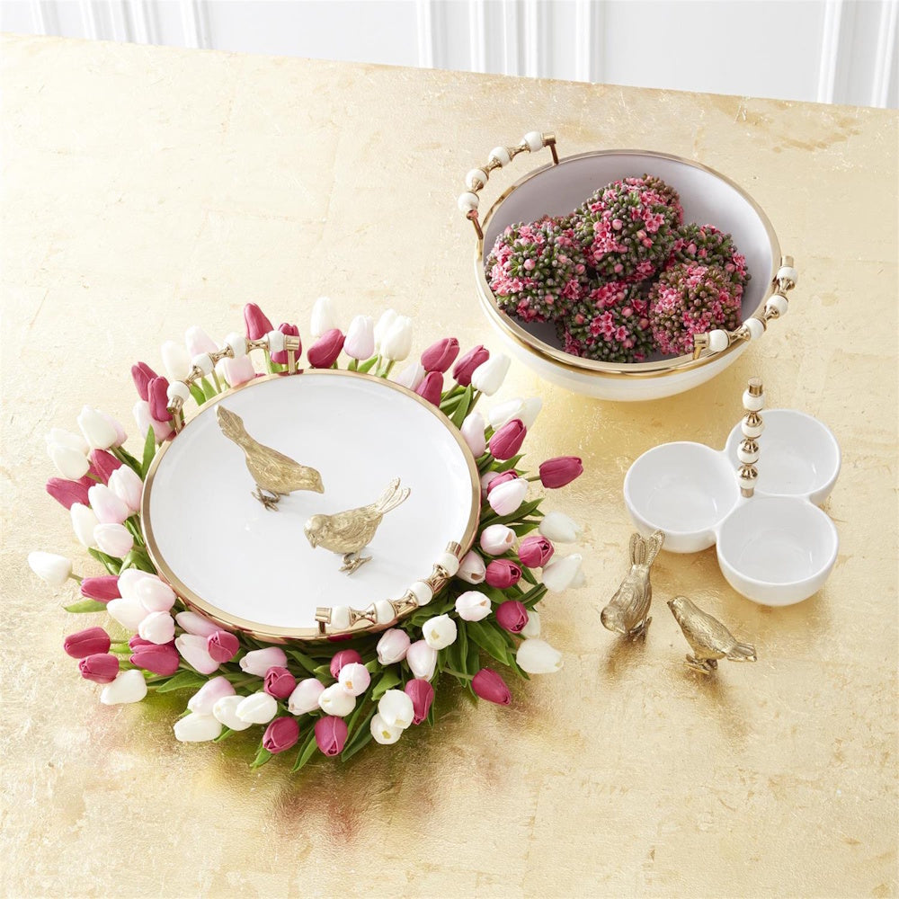 Fuchsia pink and white tulip wreath surrounding a white gold-rimmed tray with gold bird figurines on a gold table.