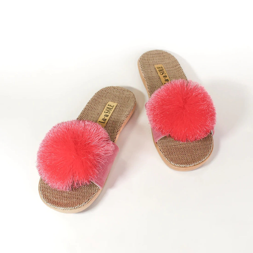 Fuchsia pom-pom slide sandals with woven jute insoles, displayed from above on a white background.