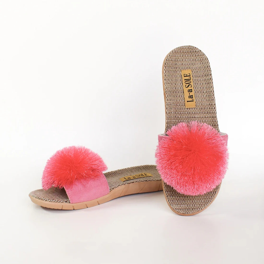 Fuchsia pom-pom slide sandals with textured woven insoles and pink straps on a white background.