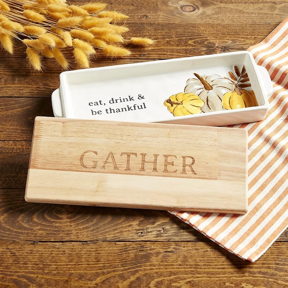 Wooden cutting board engraved with "GATHER" alongside a ceramic tray with pumpkin illustrations.