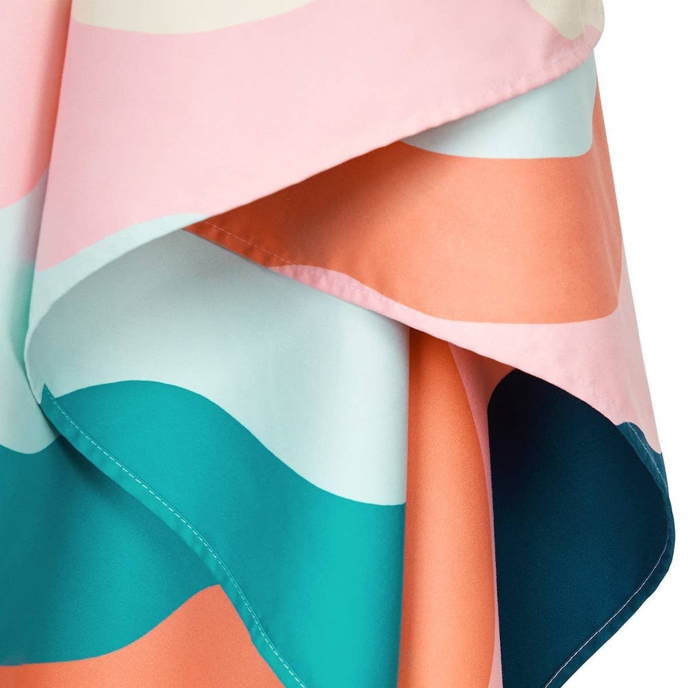 Close-up of a folded fabric featuring a colorful abstract pattern with pink, teal, and orange waves.