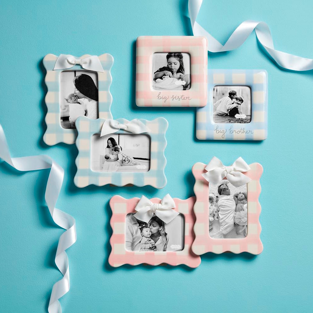 Blue and pink gingham ceramic photo frames with white bows and baby pictures on a teal background.