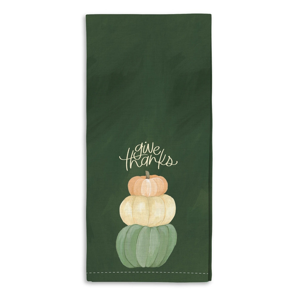 A dark green kitchen towel featuring a stack of three colorful pumpkins and the text "give thanks".