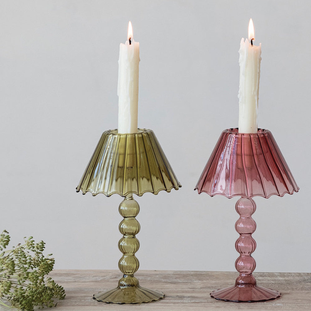 Green and pink lampshade-style glass candlestick holders with lit white taper candles.