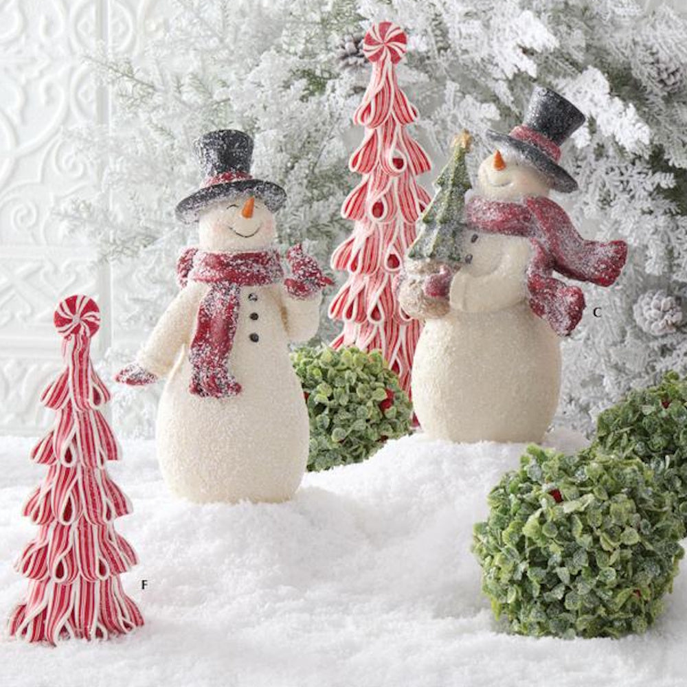 Two glittered vintage snowman figurines displayed in faux snow alongside ribbon trees and boxwood greenery.
