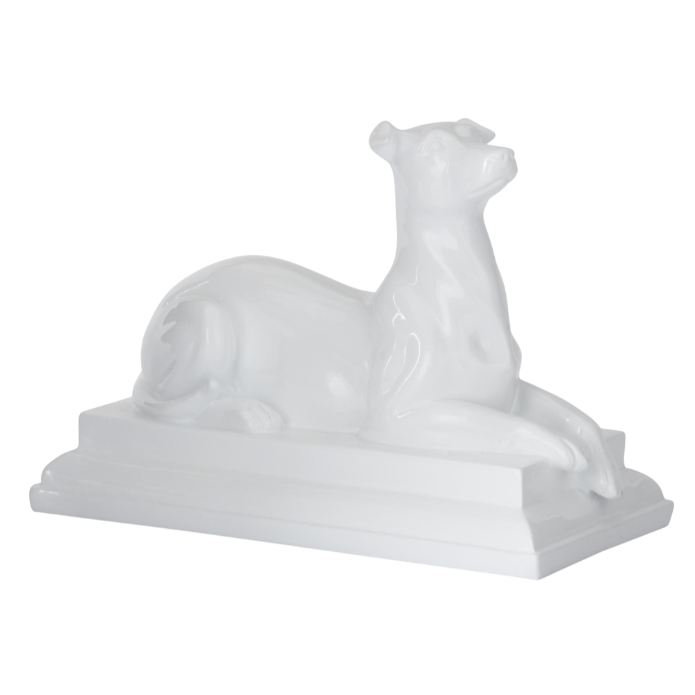 Glossy white enameled resin dog statue in a reclining pose on a rectangular pedestal base.