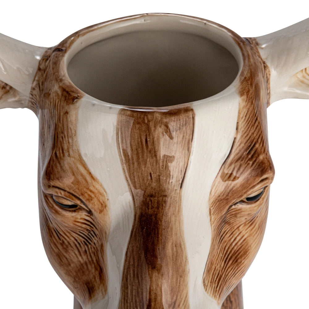 Hand-painted brown and white stoneware cow head vase with horns.
