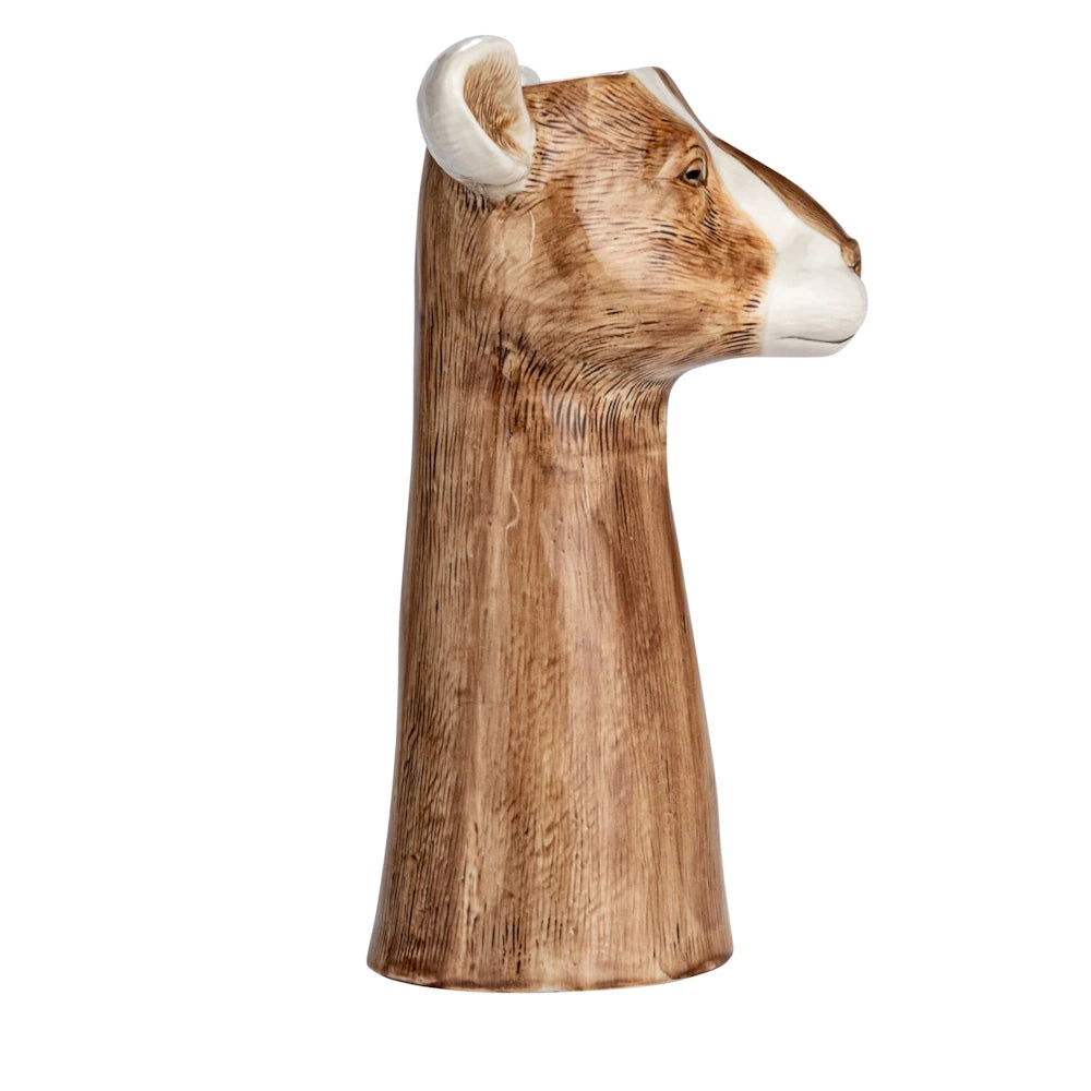 Side profile of a hand-painted brown and white stoneware cow head vase on a white background.
