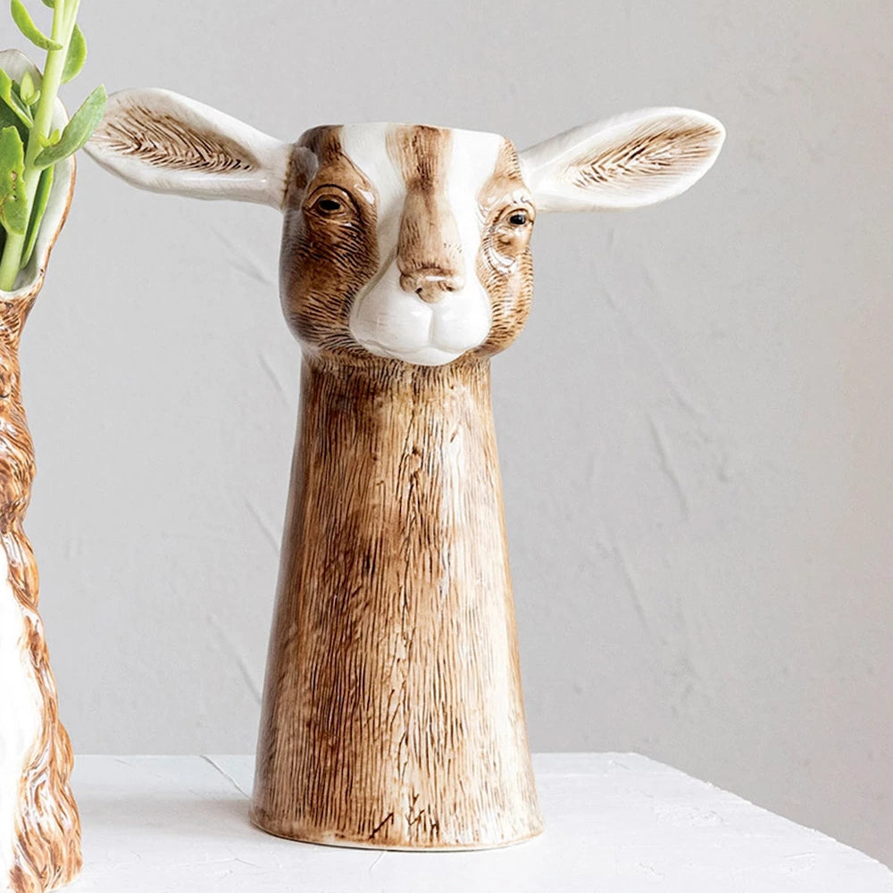 Hand-painted stoneware goat vase with brown and white textured details and long ears on a white surface.