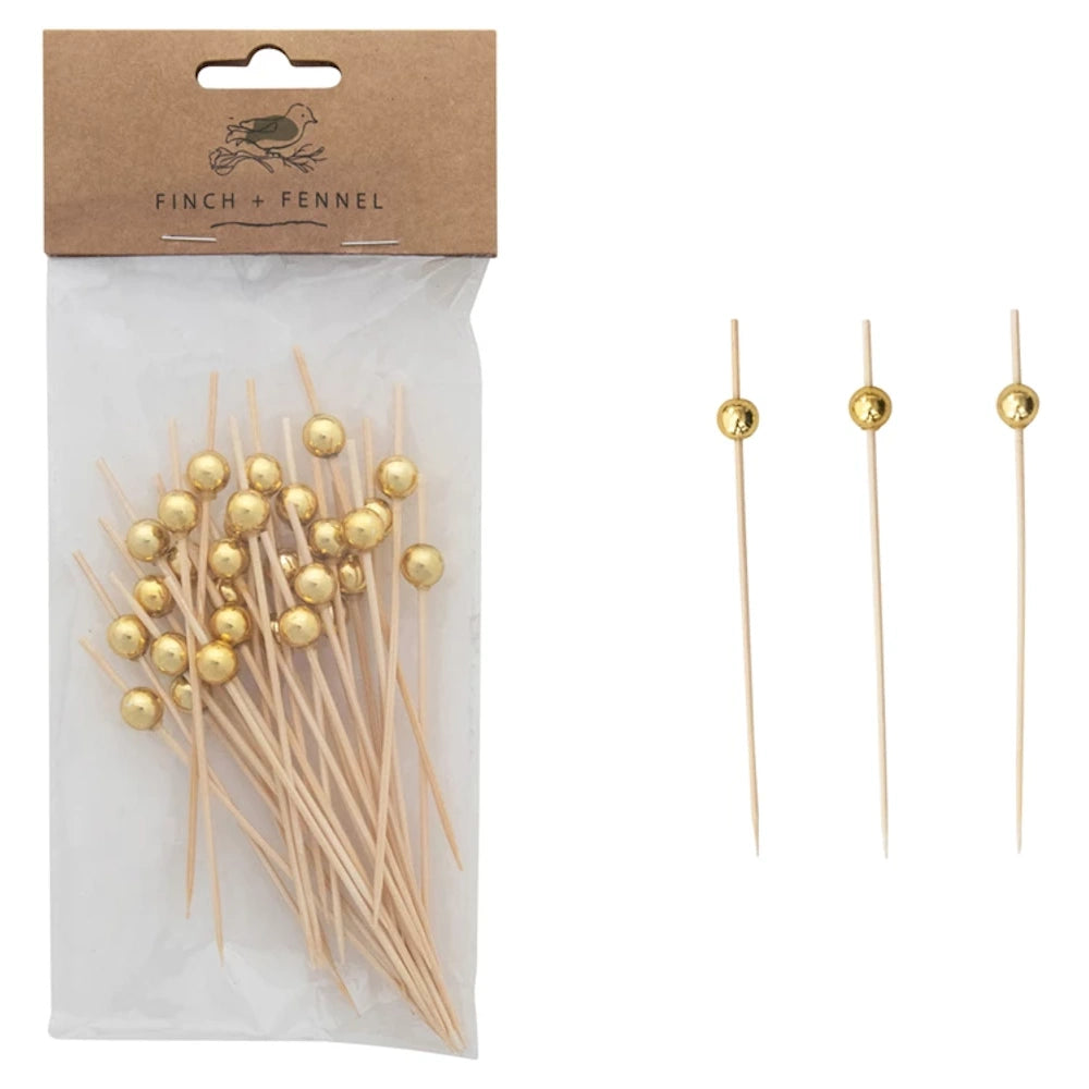 A pack of wooden picks with gold ball accents next to three loose picks on a white background.