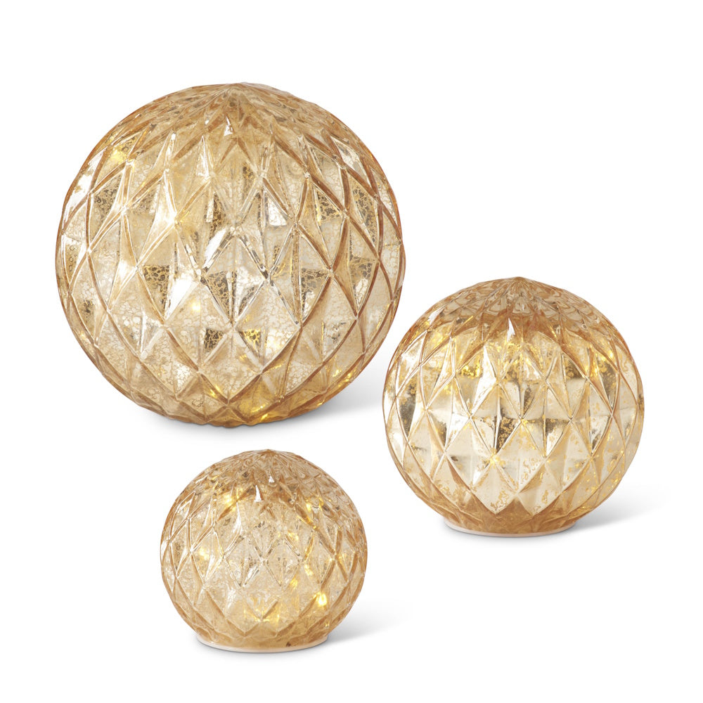 Set of three glowing gold mercury glass globes with a diamond harlequin pattern in varying sizes.