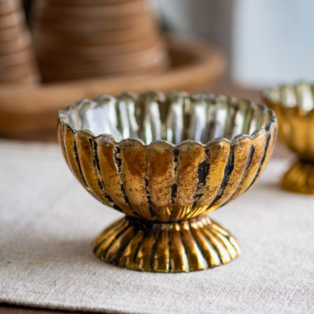 A small, distressed antique gold mercury glass pedestal bowl with scalloped, ribbed edges.